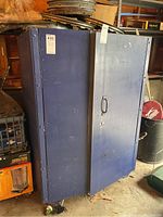 Blue metal storage cabinet with closed doors viewed from front right side in garage setting.