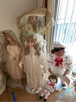 Four dolls including bride doll and sailor dolls shown with plastic covers on some dolls, viewed near window light.