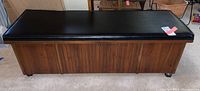 Front view of closed cedar chest showing padded black vinyl top and wood veneer front panels
