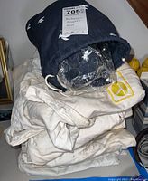 Stack of white and navy mechanic coveralls with airline logos, showing staining and wear, labeled with auction tag 705