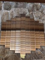 Wall mirror with a unique stair-step vertical panel design creating an overall scalloped shape, shown hanging against a stone wall with visible ceiling beams.