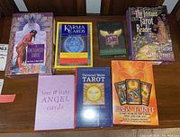 Overview of all mystical card sets and related books laid out on a wooden surface showing variety of deck types and themes.