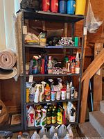 Front view of first metal utility shelf filled with household cleaners, sprays, and bottles.