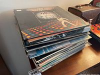 Stack of various vinyl LP albums showing some album cover edges and corner wear.