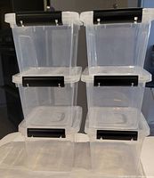 Front view of three pairs of clear storage bins stacked, showing size and handle color