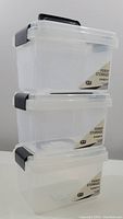 Stack of three clear plastic storage bins with black handles and locking lids, showing front and side views