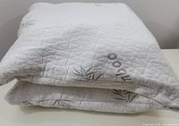 Folded view of the two white bamboo pillows showing quilted texture and bamboo plant motifs.