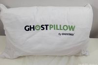 Front view of white Ghostpillow with embroidered logo in green and black.