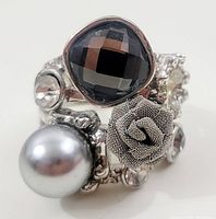 Front detail showing black faceted stone, silver-grey faux pearl, clear rhinestones, and fabric rose embellishment on silver-tone band.
