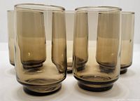 Five smokey brown vintage Dominion Glass juice glasses arranged in a close group, showing cylinder shape and tinted glass.