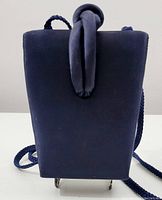 Front view of vintage evening handbag in navy blue satiny fabric showing trapezoidal shape with fabric knot handle and long twisted rope strap.