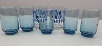 Front view of all six vintage juice glasses showing two patterned and four solid blue designs