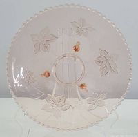 Top view showing the full round face of the pink glass footed bowl with maple leaf and orange floral etchings.