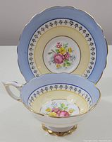 Photo of cup and saucer showing blue, yellow, and white bone china with a floral pattern and gold trim.