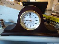 Front view of Bulova mantel clock showing overall wood finish and clock face with Roman numerals and gold trim