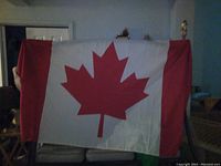 Photo of a large Canadian flag held up indoors, showing full flag dimensions and design.
