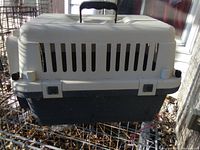 Closed pet carrier, showing ventilation slits and handle on top.