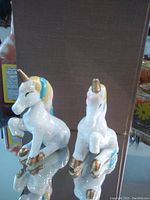 Front and side view of the unicorn salt and pepper shakers showing detailed features including gold accents and pastel colored mane and tail.
