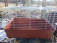 Side view of vintage small animal cage showing wire bars and plastic base