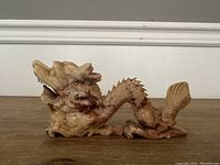 Side angle showing the dragon's detailed face with open mouth and visible teeth, textured scales along the body and tail fin.