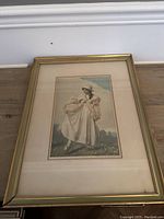 Full view of framed lithograph or painting featuring a woman in period clothing, showing overall condition and frame detail.
