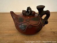 Full side view of the brown Yixing Zisha teapot showing vine and leaf decorations and tree stump style handle