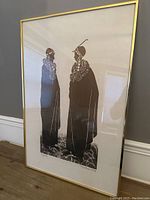 Full view of framed African print showing two adorned figures standing and facing each other