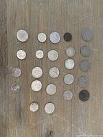 Full display of 22 coins laid out on wooden surface showing various designs, sizes and conditions.