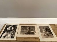 Full view of the three framed black and white sketches laid out on the floor showing their relative sizes and details.