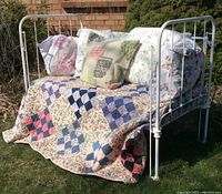 Overall styled view with quilt and pillows on white cast iron daybed bench