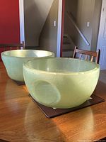 Two large vintage fibreglass planters with green/yellow color visible on a wooden dining table indoors.