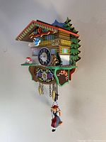 Right-side angled view showing roof, side tree, mushroom, deer, pine cone weights, chain and pendulum figurine