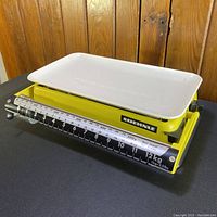 Oblique front angle showing scale platform, sliding scale bar, and SOEHNLE branding on the bright yellow base.