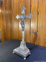 Side angled view of vintage silver standing crucifix showing figure of Christ and base