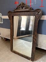 Full view of antique wooden framed mirror showing overall shape and size with visible wear on wood and glass.
