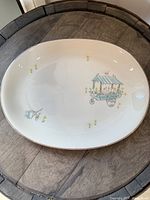 Full view of the oval platter on a wooden surface showing the floral cart design.