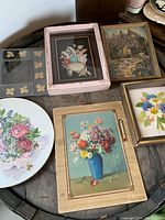 Overview of all floral artworks displayed on table showing variety of styles and frames.