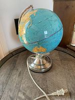 Front angle view of the vintage globe lamp showing the globe and metal base with attached power cord and plug.