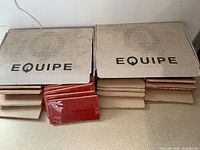 Two sealed cardboard boxes labeled Equipe with stacked red subway tiles partially visible under the boxes.
