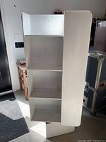 Front view of the white rotating bookcase showing shelves and rounded side panels.