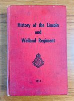 Front cover of red hardcover book titled 'History of the Lincoln and Welland Regiment', with regimental insignia and 1954 publishing year on the front.