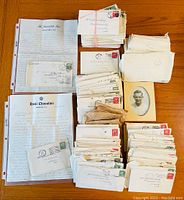 Overall view showing multiple handwritten letters, stacks of envelopes, and a black-and-white photo arranged on wood surface.