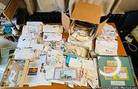 Overview of a table covered with multiple boxes, loose envelopes, stacks of letters and loose stamps spread out