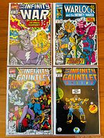 Photo of four Marvel comic books: Infinity War #6, Warlock and the Infinity Watch #9, Infinity Gauntlet #4, and Infinity Gauntlet #6, showing colorful front covers with characters like Thanos and Adam Warlock.
