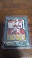 Front of Justin Fields rookie card in plastic sleeve showing player in white uniform with football.