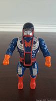 Front view of the Dragstor action figure showing blue body, orange gloves and boots, silver chest armor with red butterfly emblem, and black helmet with silver faceplate.