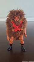 Front view of 1980's Grizzlor action figure standing upright, showing detailed orange plastic limbs, textured brown fur covering torso and head, red chest armor, and black boots with colored details.