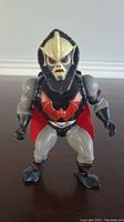 Front view of vintage 1980's Hordak action figure in gray with black armor, red bat emblem on chest, and red cape.