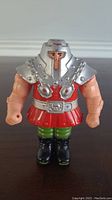 Front view of the Ram Man vintage 1980's MOTU He-Man action figure showing silver helmet and chest armor, red skirt, green pants, black boots, and flesh toned arms.