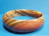 Front view showing the polished, multi-toned brown and beige swirled stone bangle bracelet.